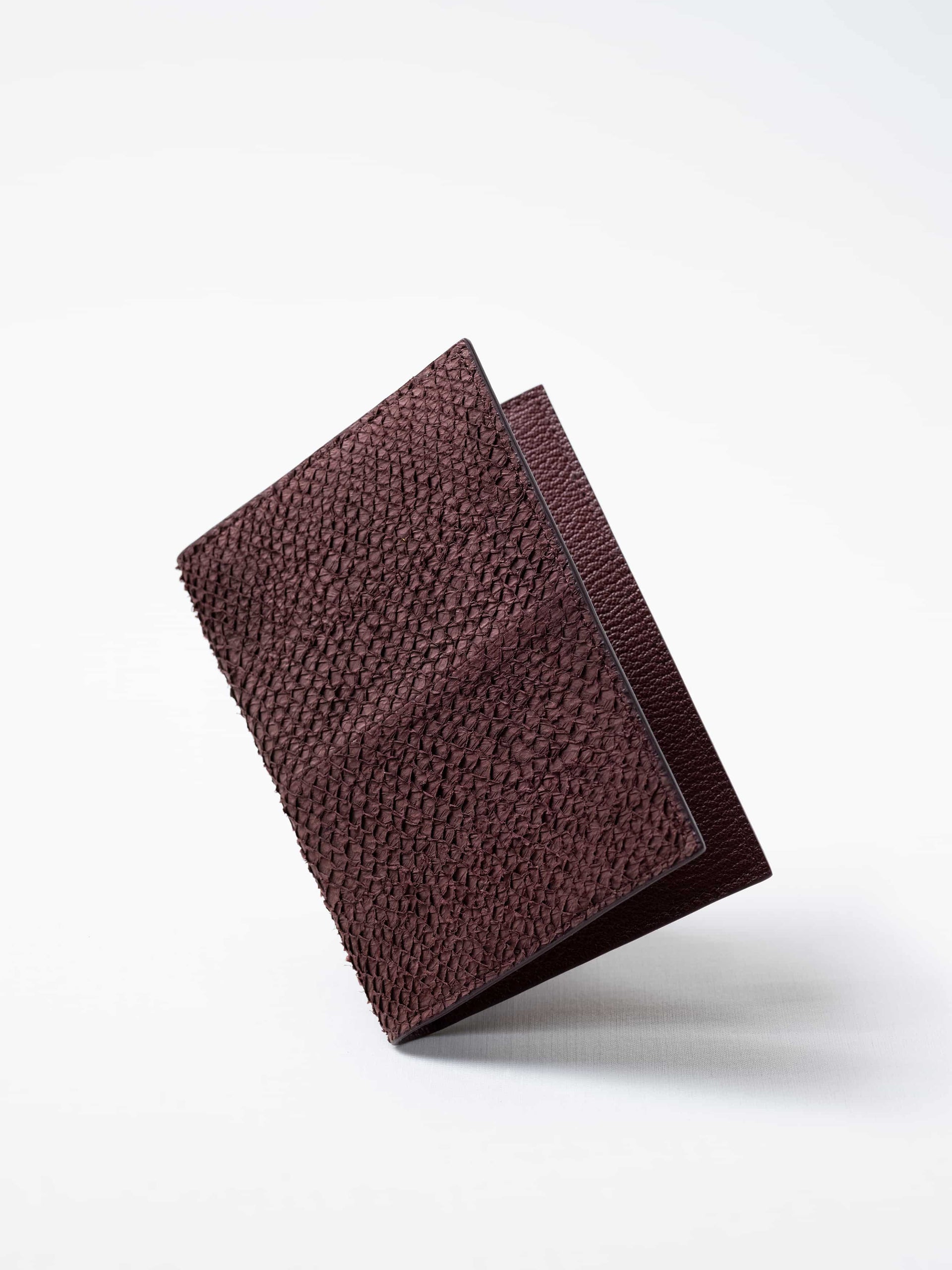 Vega luxury travel wallet in burgundy salmon leather, closed view highlighting the textured fish leather exterior, handcrafted in Sweden by Kristian Eddé