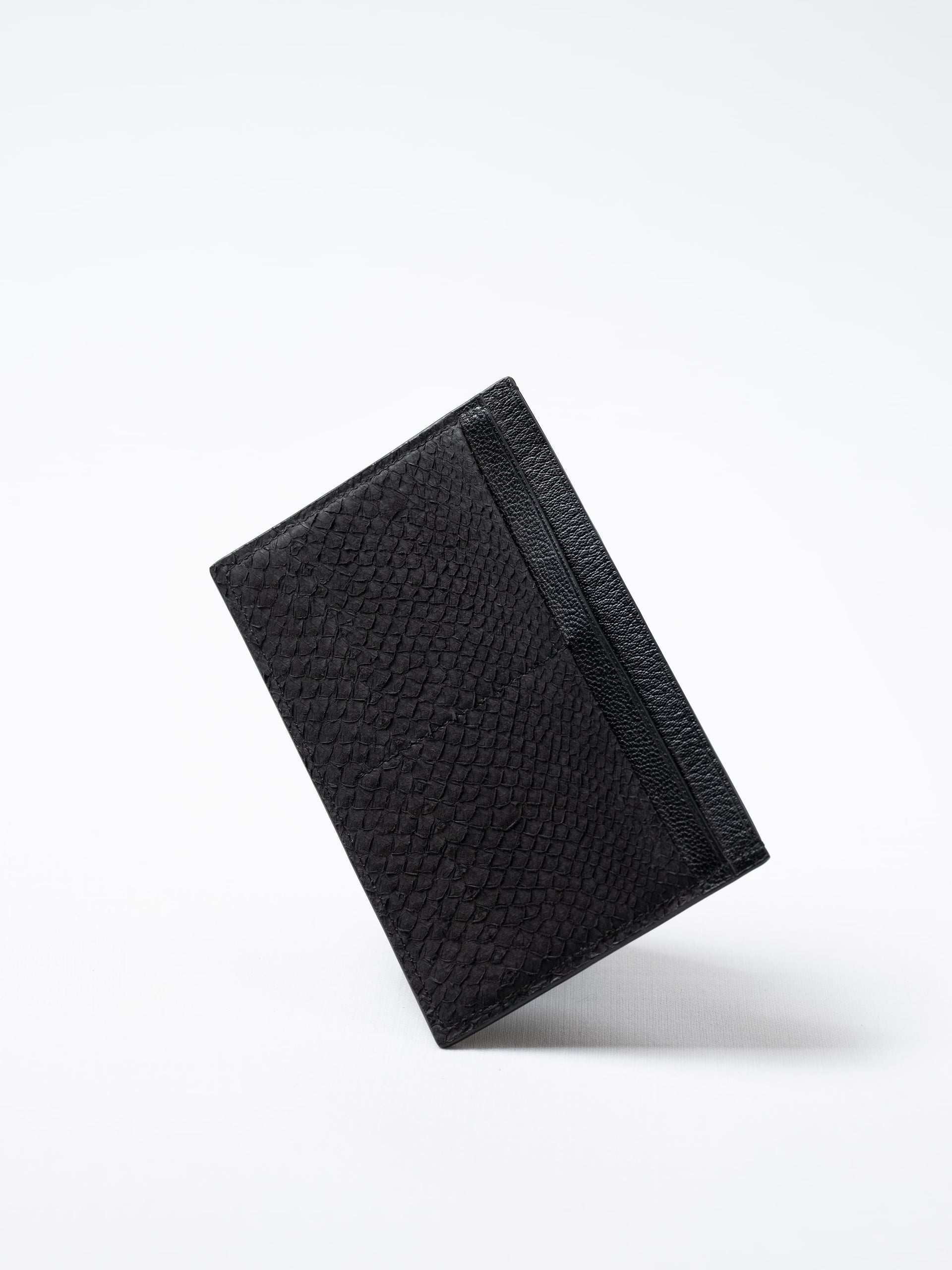 Discover the black Aurora travel wallet, handcrafted in sustainable salmon leather. A luxury accessory designed for passports, cards, and modern journeys
