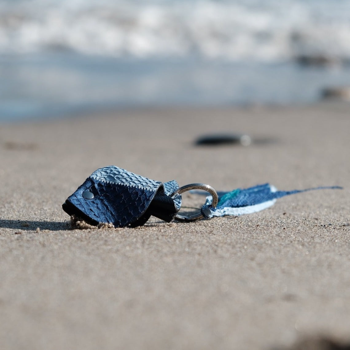 Side view of blue salmon leather fish key charm from the California Canvas Collection by Kristian Eddé, showing handcrafted texture and silver or gold hardware