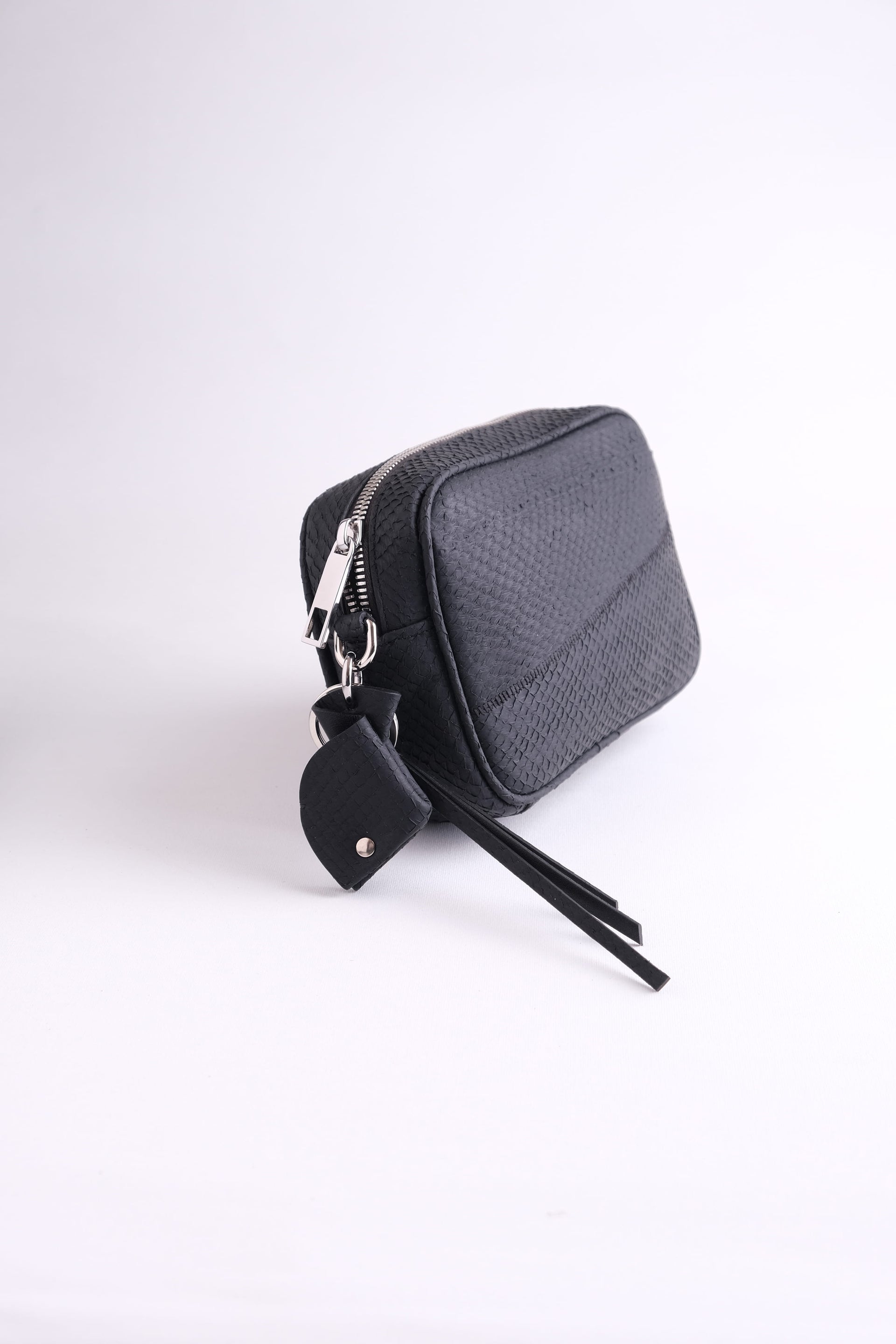 Side view of Kolga camera bag in arctic black salmon leather, featuring clean lines, spacious depth, and fish leather key charm, sustainable luxury by Kristian Eddé