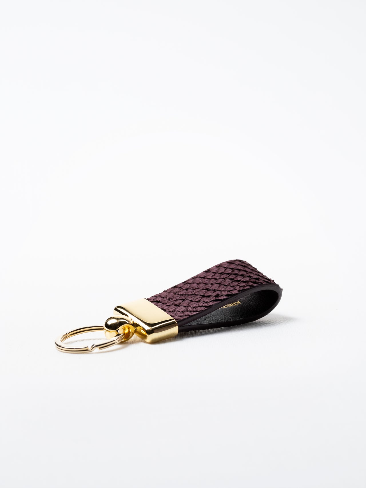 Side view of burgundy salmon leather key ring, highlighting natural grain and gold-plated hardware