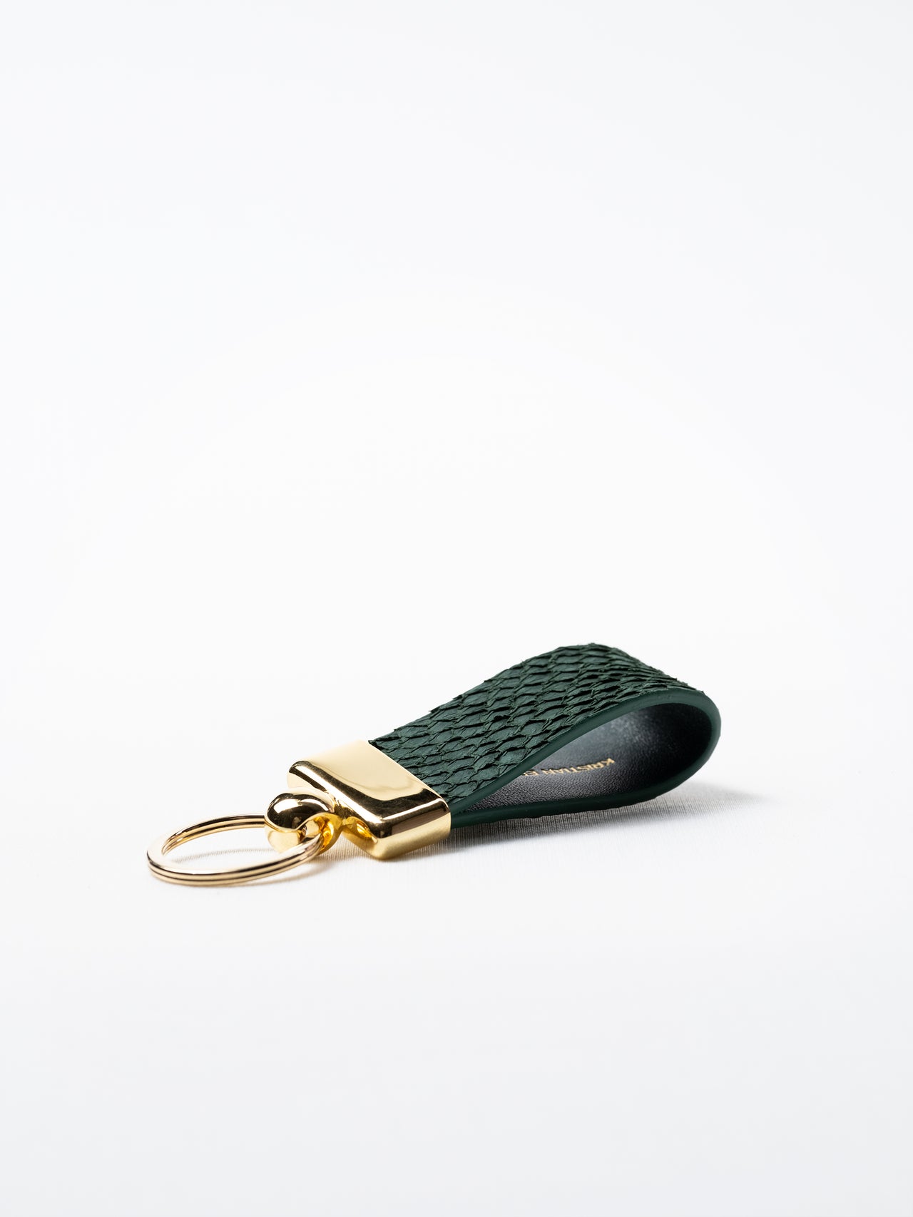 Side view of kelp green salmon leather key ring, highlighting natural grain and gold-plated hardware