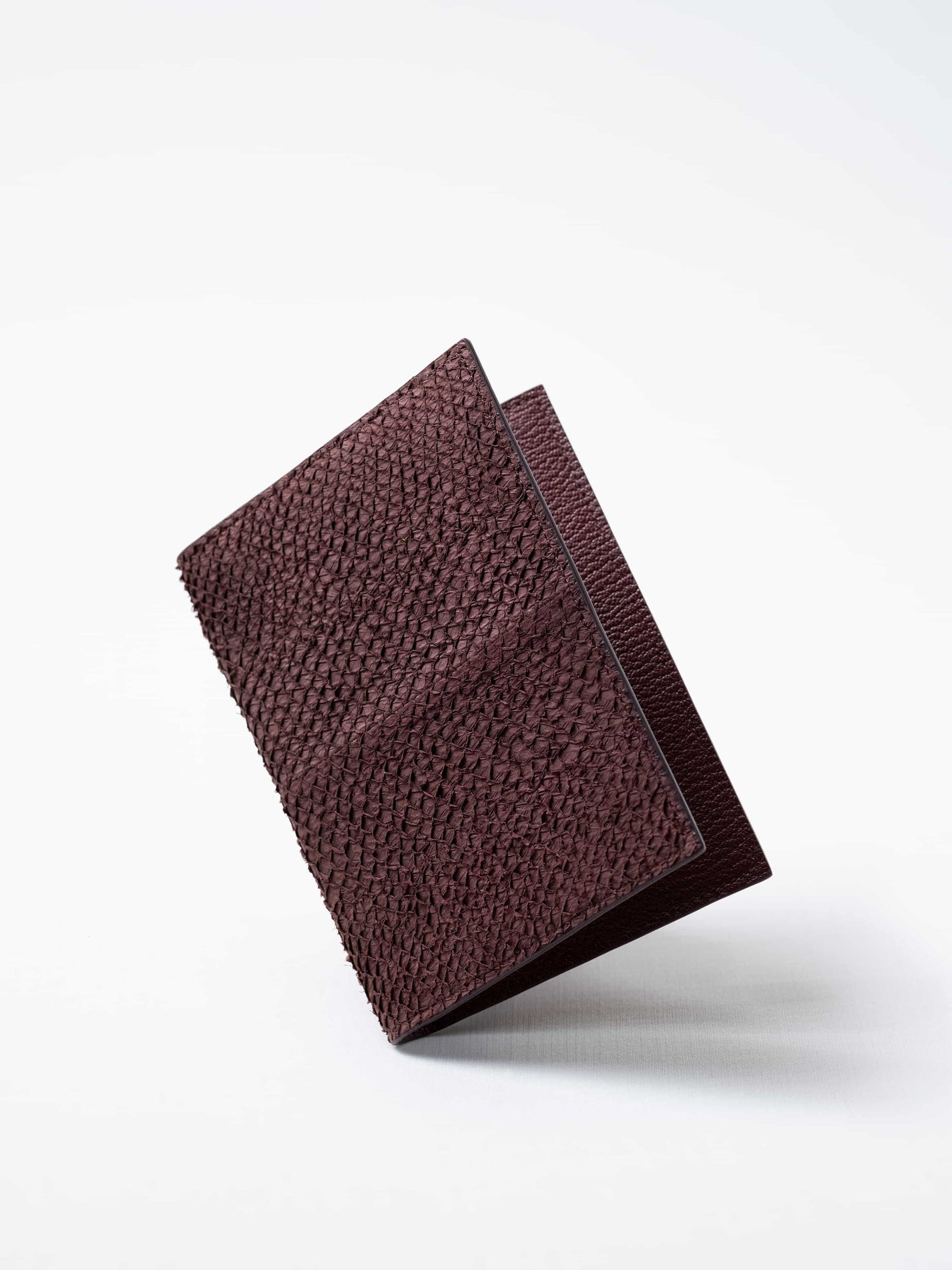 Vega luxury travel wallet in burgundy salmon leather, closed view highlighting the textured fish leather exterior, handcrafted  in Sweden by Kristian Eddé