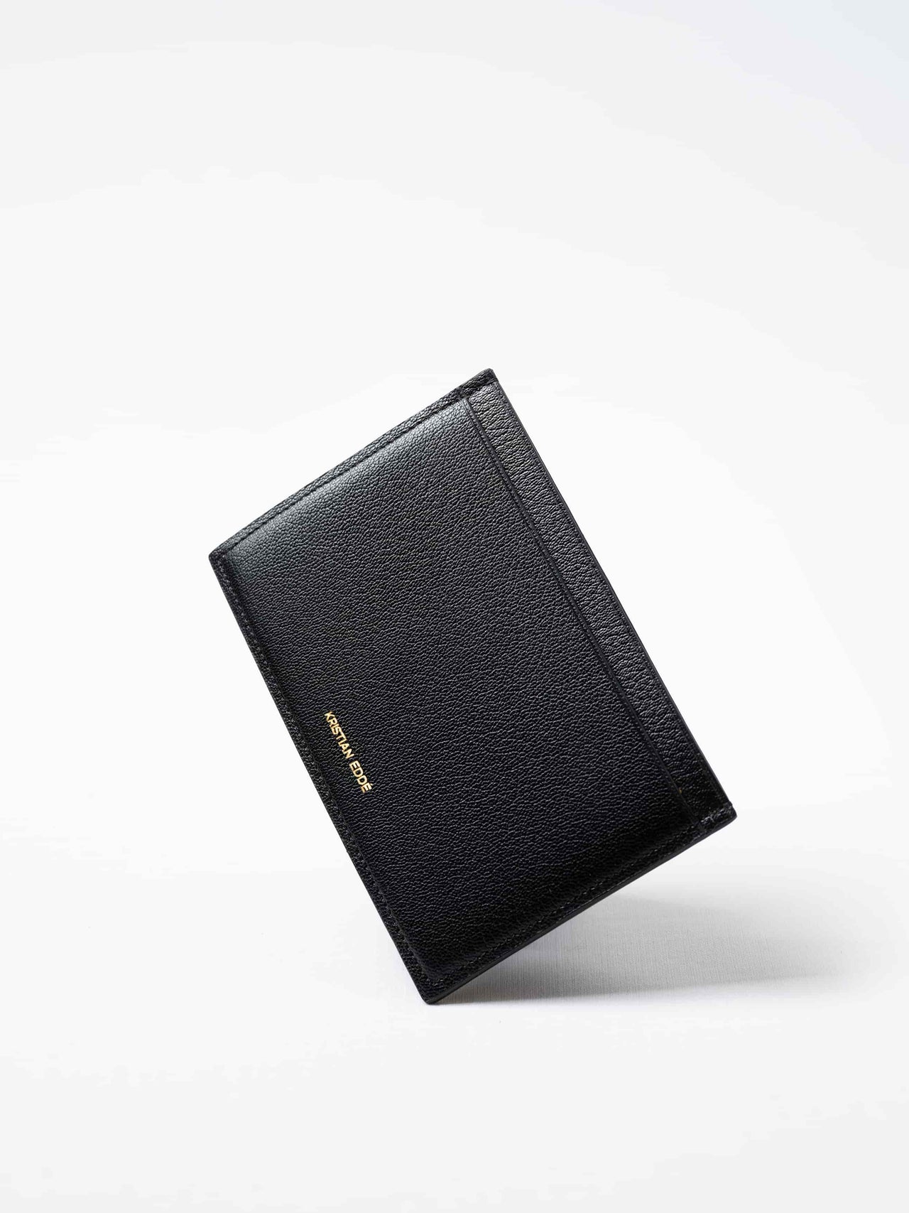 Black Aurora travel wallet in fish leather with golden logo. Handcrafted in Stockholm, this luxury accessory elevates passports, cards, and travel style