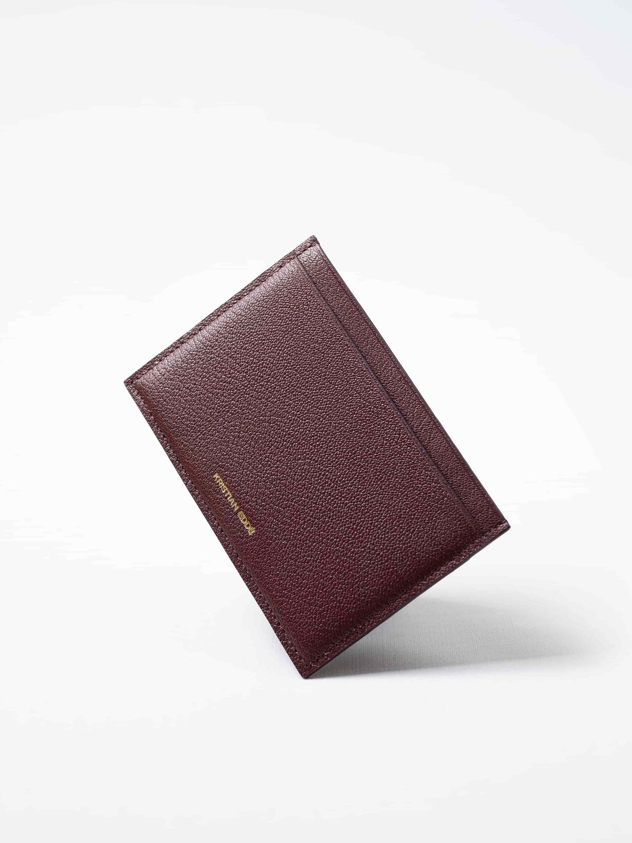 Burgundy Aurora travel wallet in fish leather with golden logo. Handcrafted in Stockholm, this luxury accessory elevates passports, cards, and travel style