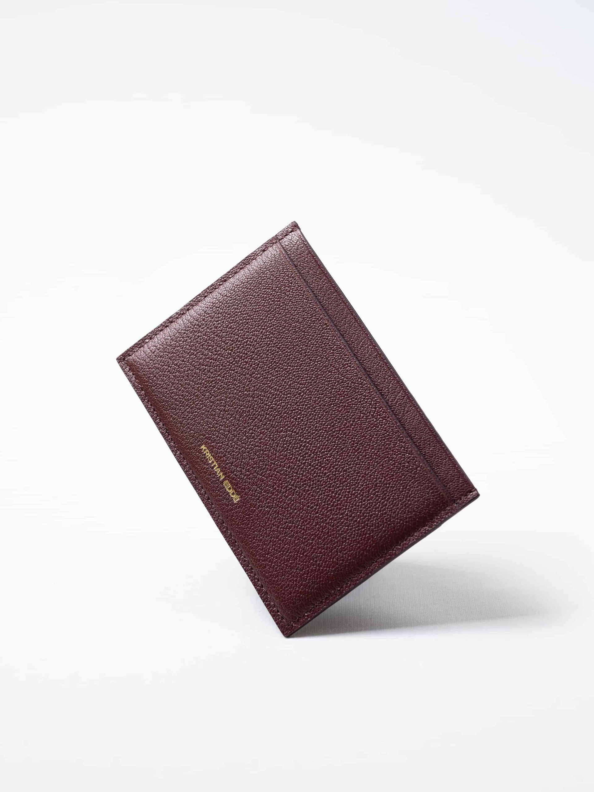 Burgundy Aurora travel wallet in fish leather with golden logo. Handcrafted in Stockholm, this luxury accessory elevates passports, cards, and travel style