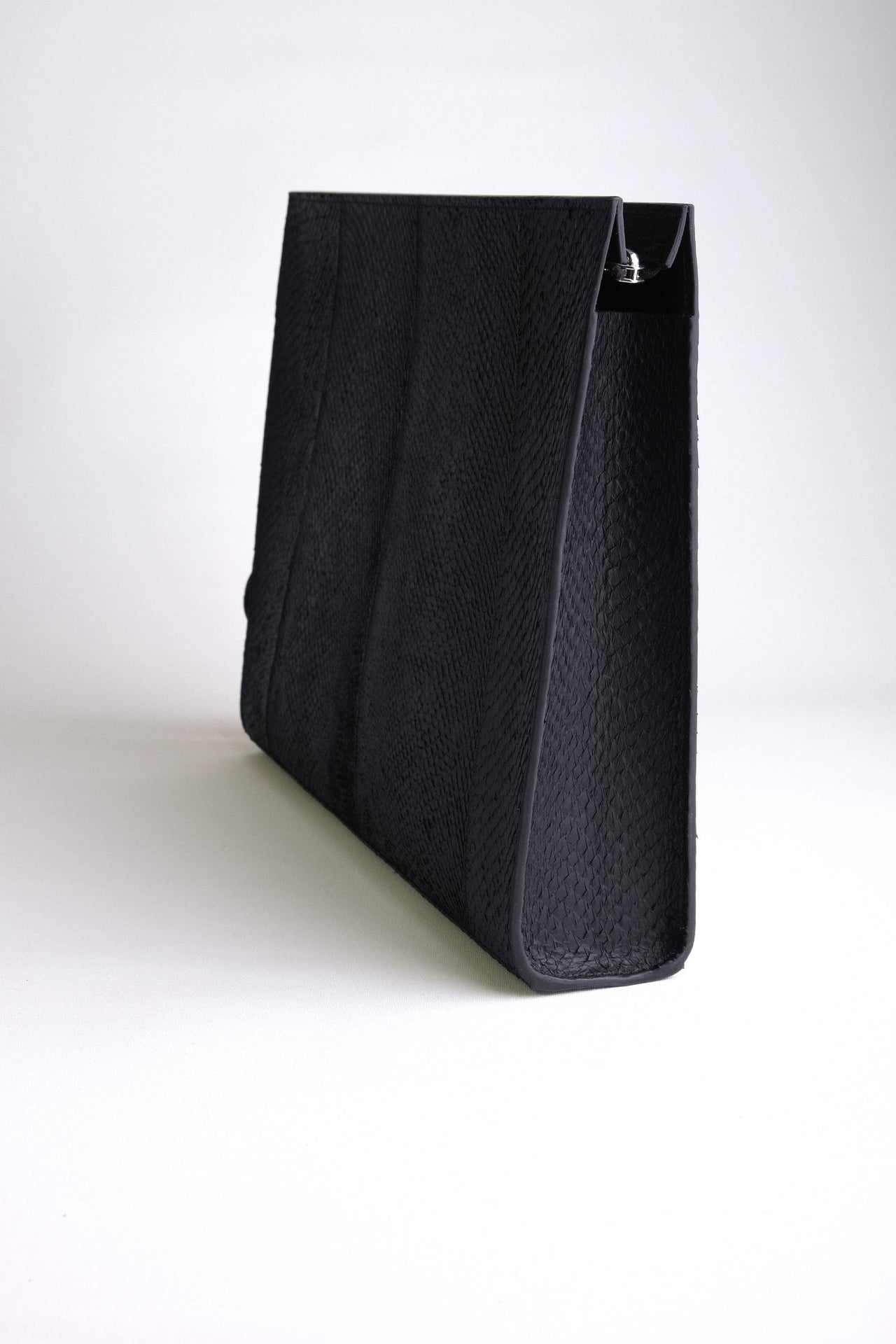 The back view of the Baltic Clutch showing gusset construction and structured silhouette in black salmon leather