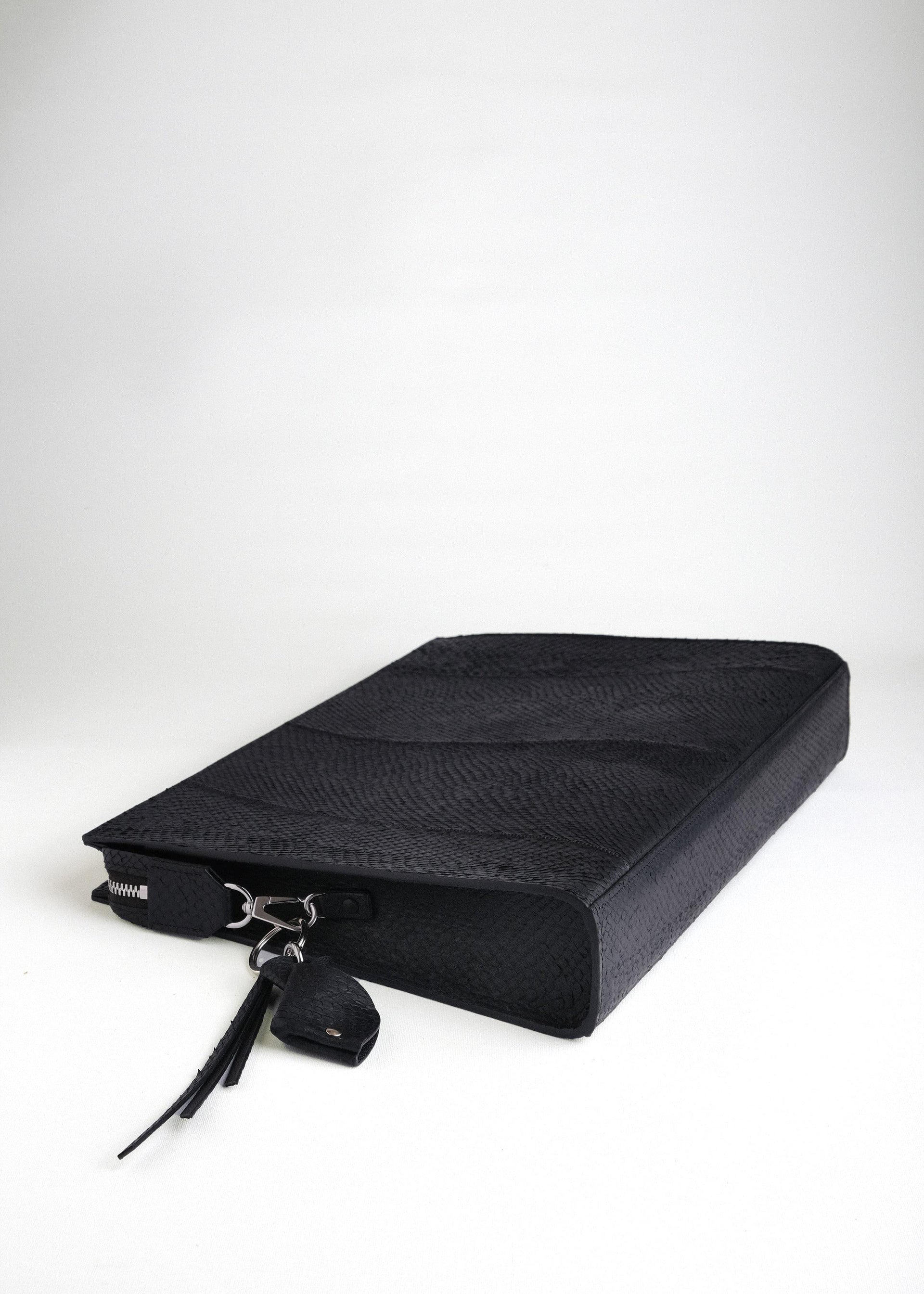Baltic Clutch lying flat with bottom side visible, featuring detachable fish leather key charm and refined detailing