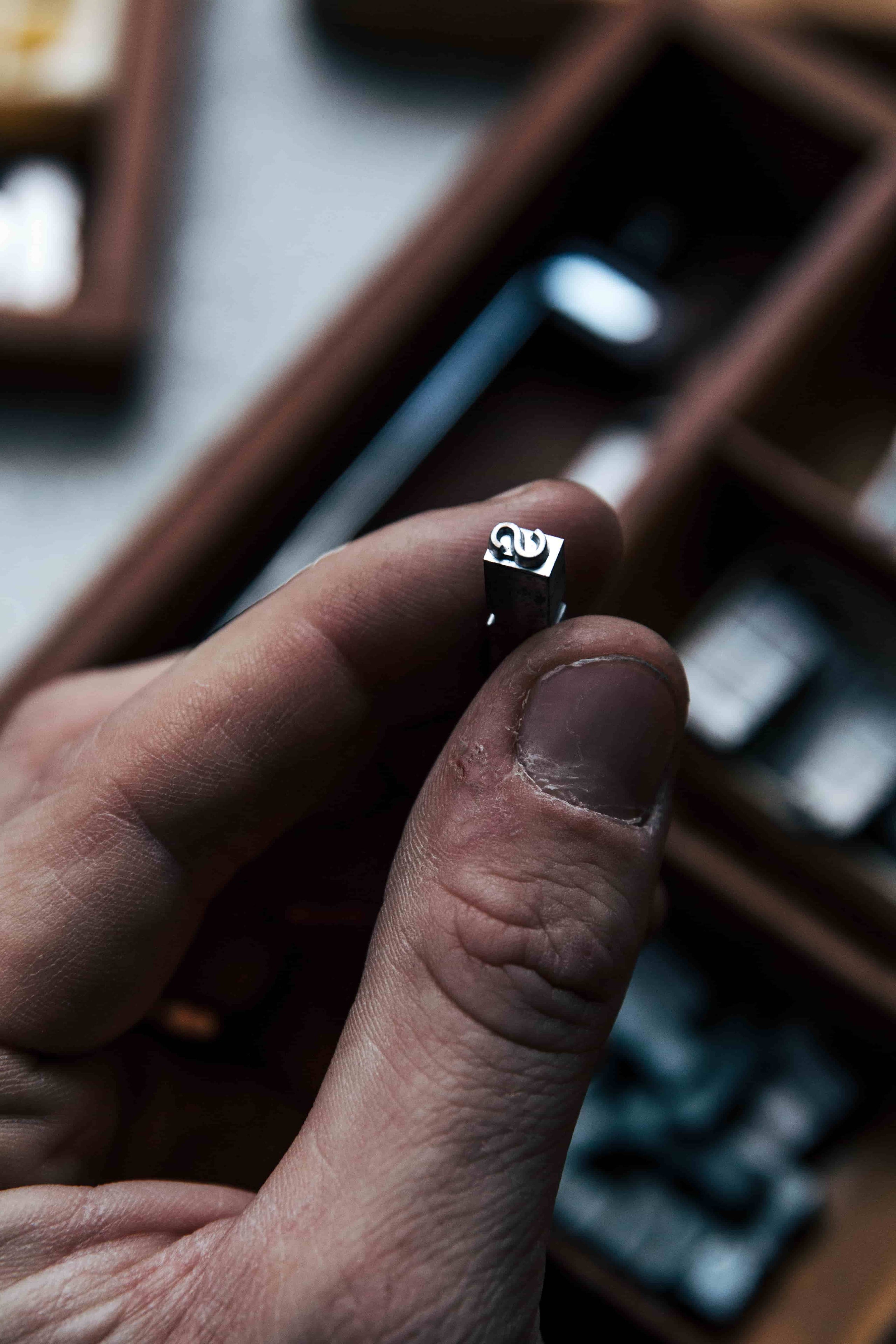 Close-up of Kristian Eddé artisan holding the News Gothic font sample for leather embossing, showcasing detailed typography for personalized monogramming.