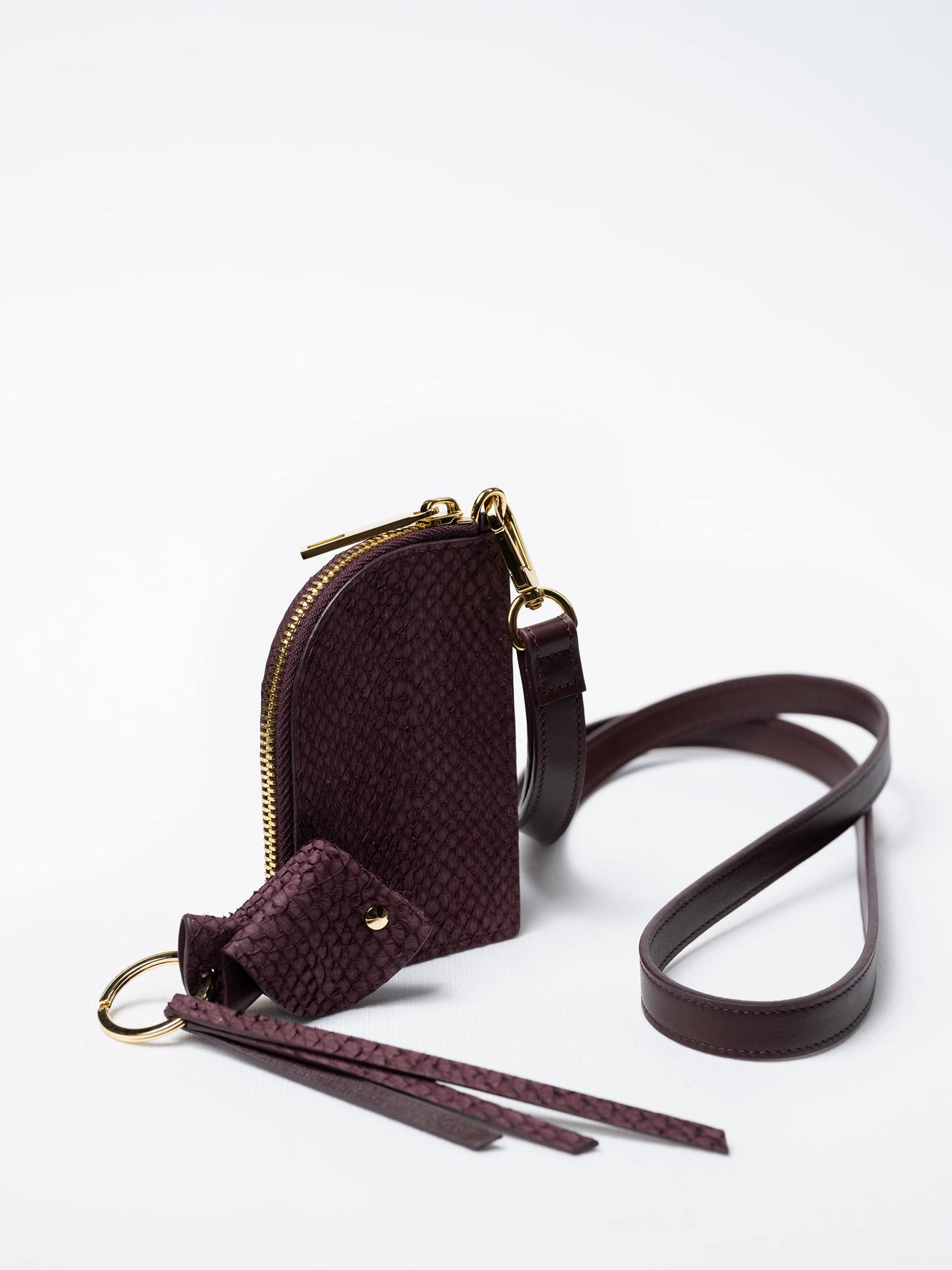 Salma zipper wallet on strap in burgundy fish leather with gold zipper and key charm – sustainable luxury by Kristian Eddé