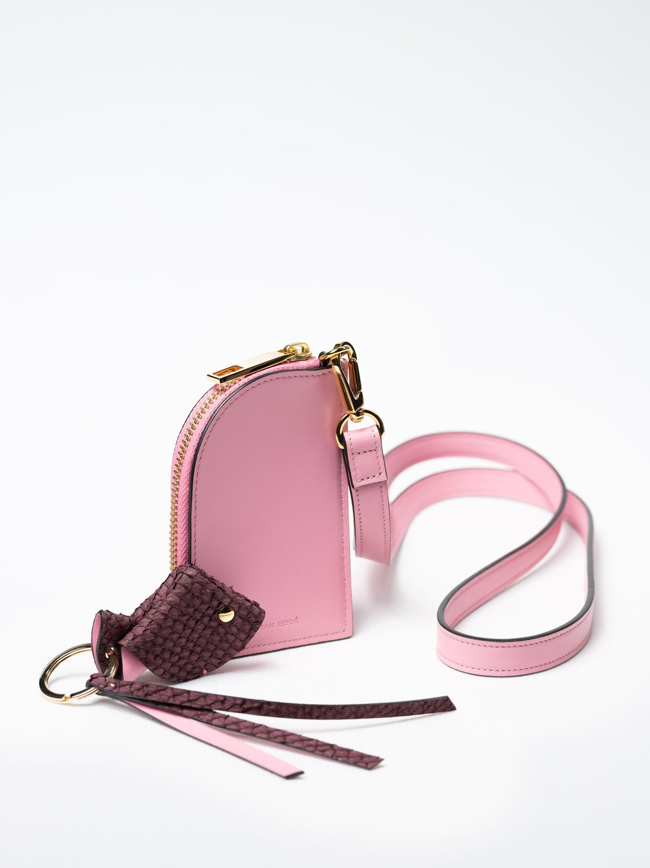 Salma zipper wallet on strap in pink nappa leather with gold zipper and a fish leather key charm, sustainable luxury by Kristian Eddé
