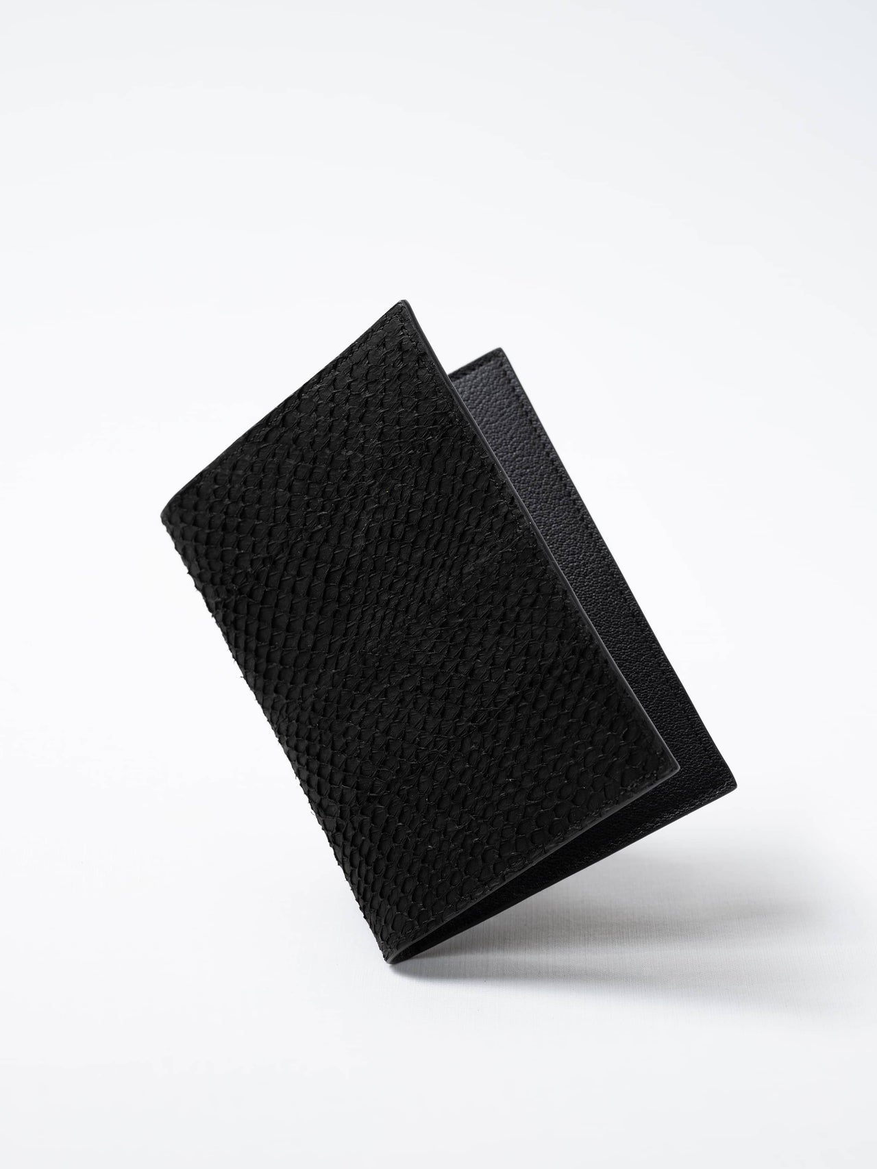 Trawler Fold Passport Holder in black fish leather, closed view highlighting the textured fish leather exterior, handcrafted in Sweden by Kristian Eddé