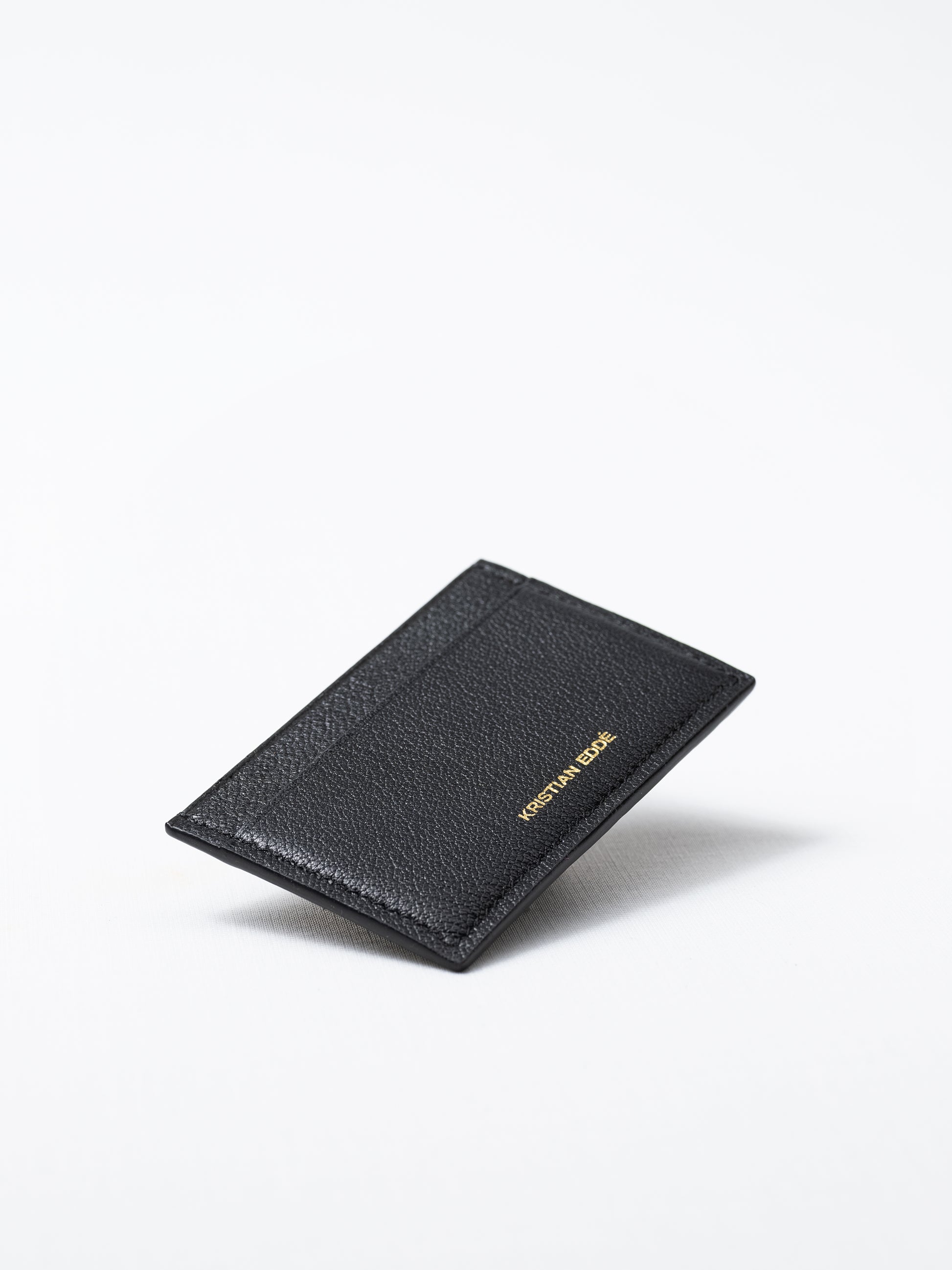Bothnia black card holder made of salmon leather, back view of gold logo on white background