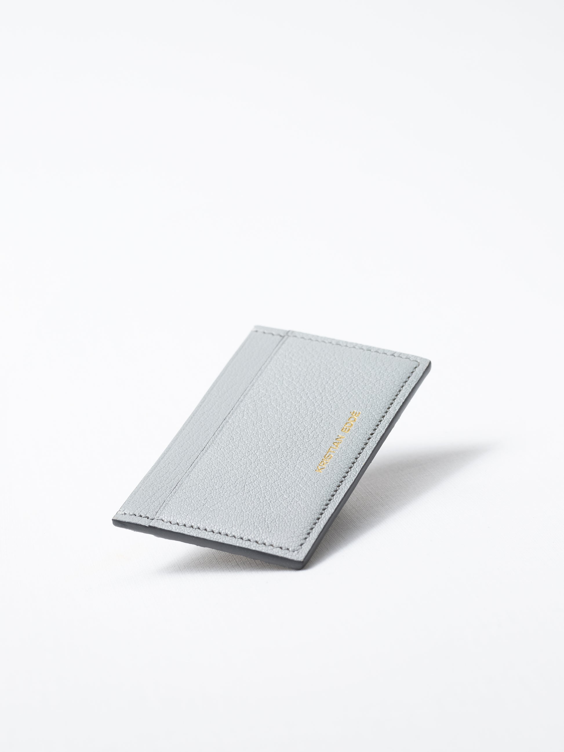 Bothnia himalayan gray card holder made of salmon leather, back view of gold logo on white background